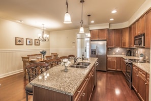 Enjoy cooking in this well-equipped kitchen with a central island, oven, and stainless steel sink.