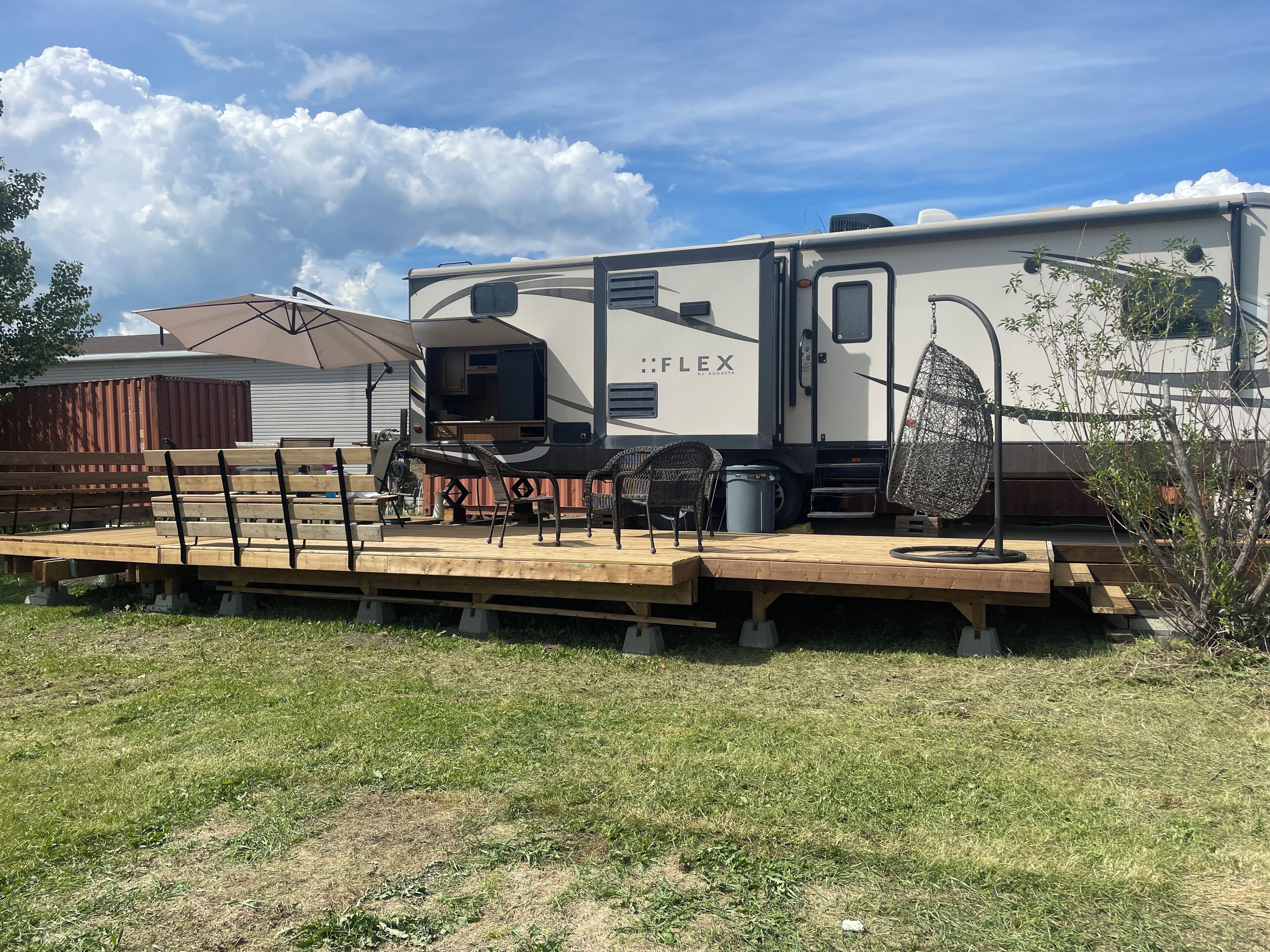 A recreational vehicle with a kitchen area, a dining table, and outdoor seating.