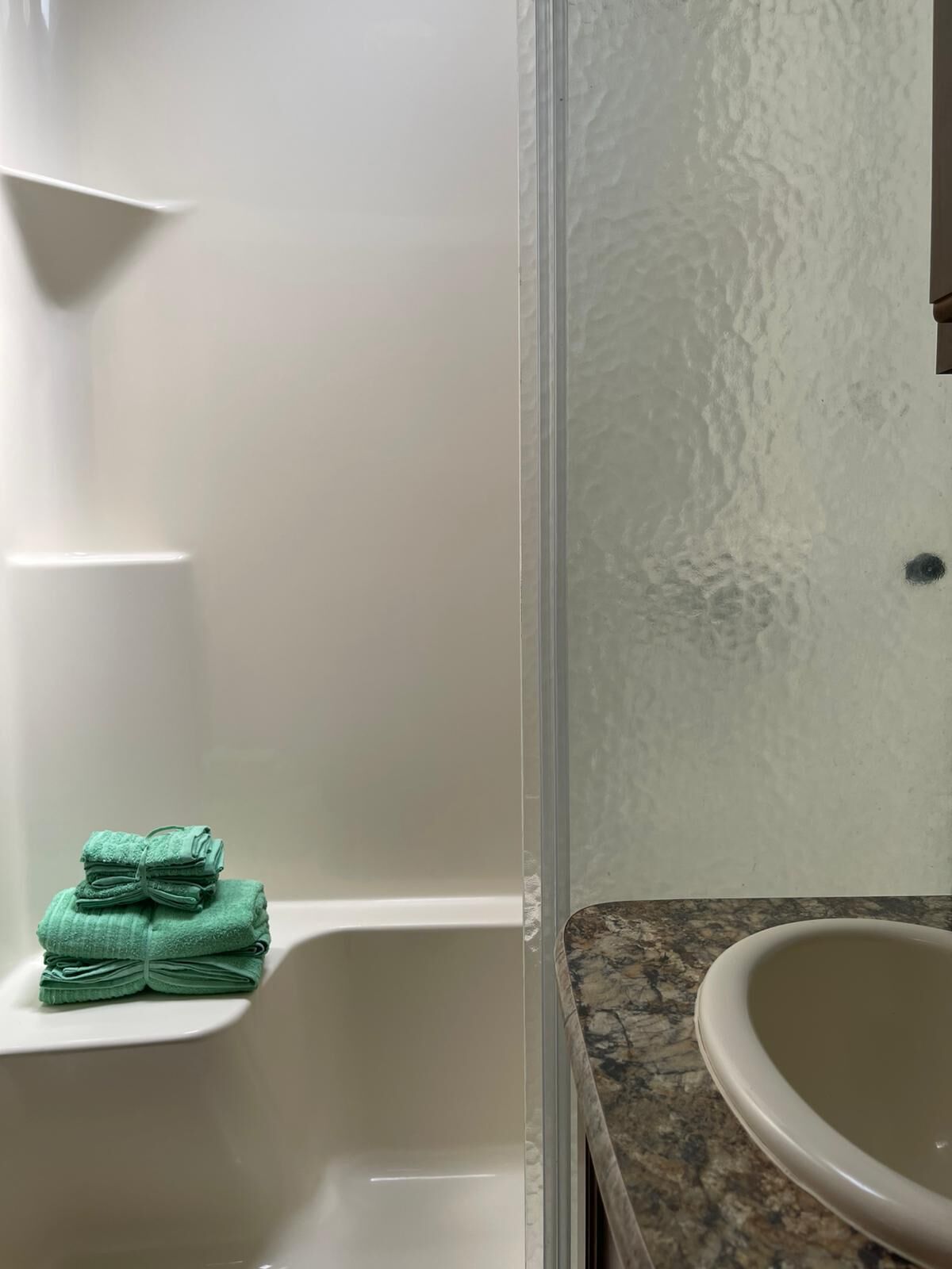 Un bagno con una vasca da bagno bianca, un asciugamano verde e un lavabo su un piano in granito.