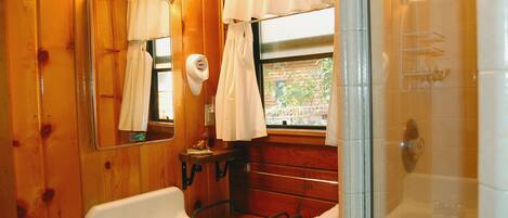 A wooden bathroom with a sink, mirror, and shower.