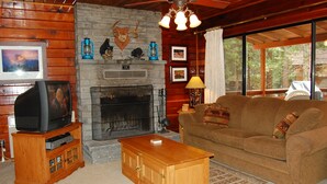 A cozy living room with a fireplace, wooden furniture, and a television.