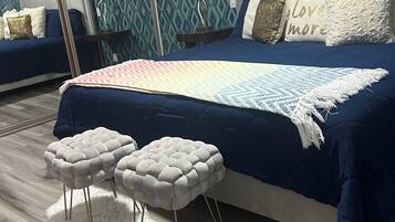 A bedroom with a large bed, two nightstands, a white fluffy rug, and a patterned wall.