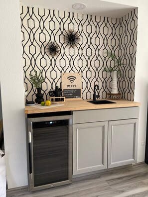 Une cuisine moderne avec un revêtement mural à motifs géométriques, un lave-vaisselle encastré et un plan de travail en bois.