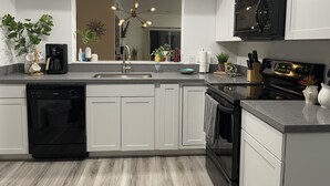 Una cocina moderna con lavavajillas, estufa, microondas y una isla grande con pileta.
