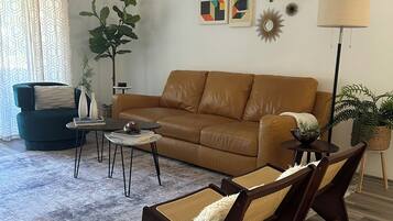 A living room with a brown leather sofa, two armchairs, a coffee table, and a floor lamp.