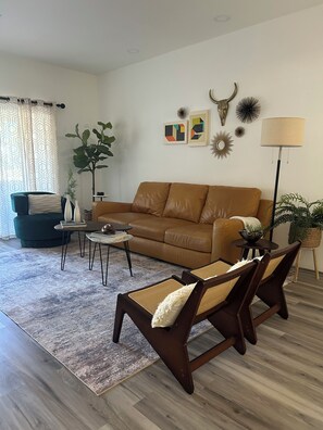 A living room with a brown leather sofa, two armchairs, a coffee table, and a floor lamp.