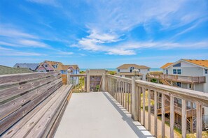 A wooden boardwalk leading to beach houses with a clear view of the ocean. - Semi-Oceanfront Dog Friendly w/ Hot Tub, Game Room, Community Pool and Tennis (Avon)