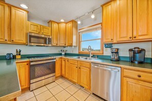A kitchen with wooden cabinets, a stainless steel microwave, a coffee maker, and a dishwasher. - Semi-Oceanfront Dog Friendly w/ Hot Tub, Game Room, Community Pool and Tennis (Avon)