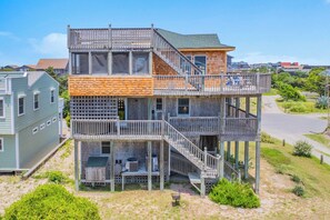 A multi-story house with a balcony, outdoor seating, and a staircase.