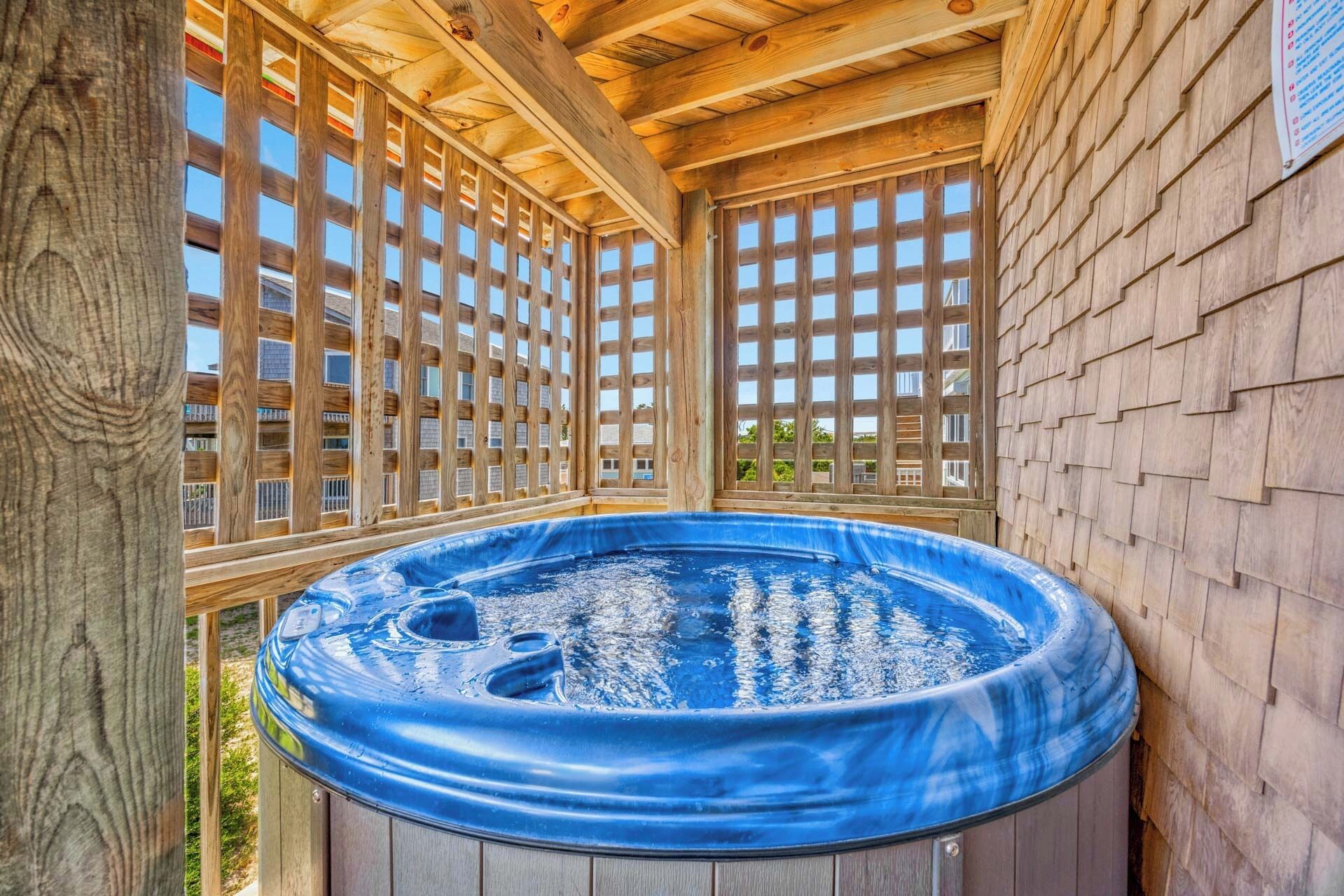 A hot tub in a wooden structure with a view of a residential area.