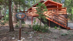 Una cabaña rústica con una escalera de madera y un letrero que indica que forma parte de The Redwood Lodge en Yosemite.