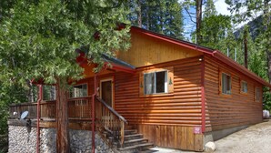 A log cabin with a wooden exterior, a front porch, and a staircase leading to the entrance.
