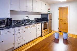 Een koelkast, een microgolfoven, een oven, kookgerei, borden en bestek