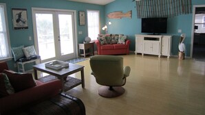 Una sala de estar con un sofá rojo, un sillón verde, una mesa de centro y un televisor.