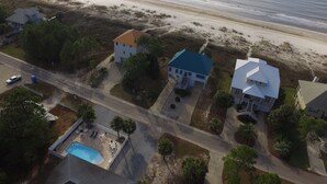 Vista aérea de una zona residencial costera con casas, una piscina y una playa.