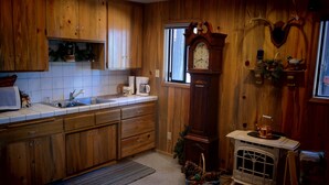 A wooden kitchen with a built-in stove, wooden cabinets, and a large wall clock. - Lakefront Romantic Getaway - The Little Blue Cabin (Westwood)