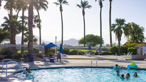 A pool area with palm trees, lounge chairs, and a clear view of mountains in the background. - Walking Distance from Coachella and Stagecoach festivals (Indio)