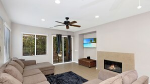 A modern living room with a sectional sofa, a fireplace, and a television mounted on the wall. - Walking Distance from Coachella and Stagecoach festivals (Indio)