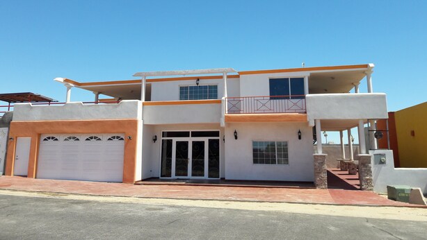 Una casa a due piani con garage, un balcone e un portico coperto.