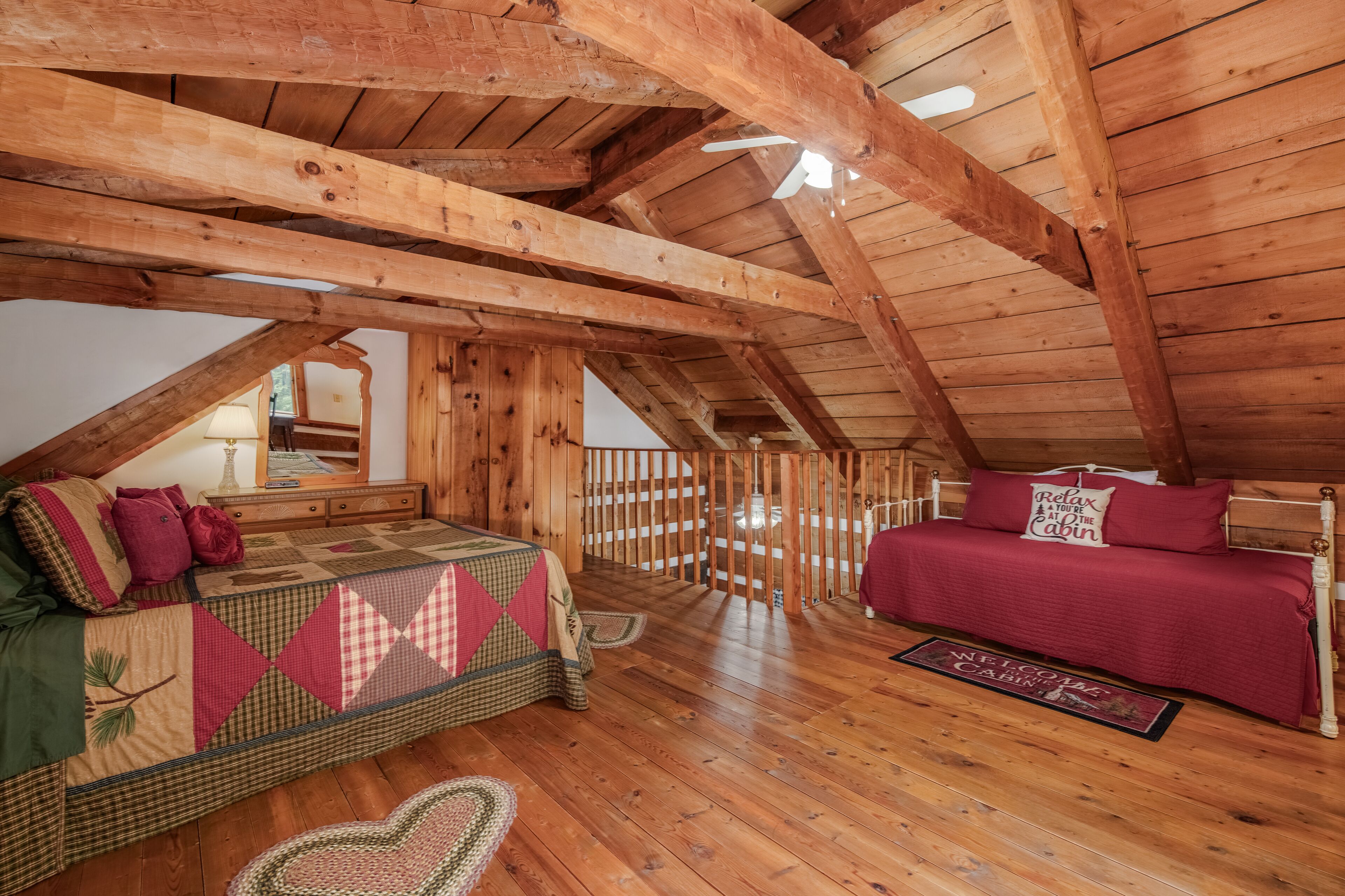 A cozy attic bedroom with wooden beams, a bed, a sofa, and a small table.