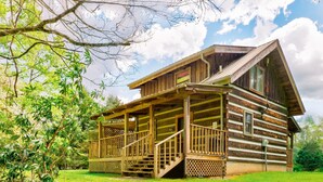 A rustic log cabin with a porch and stairs leading to the entrance. - Hearts Bursting with Love  Romantic Creekside Retreat!! (Cosby)