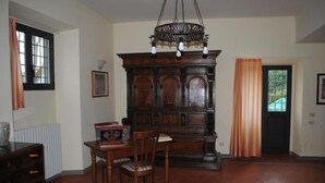 A dining area with a wooden table and chairs, a dark wooden cabinet, and a chandelier.