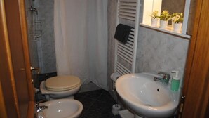 A bathroom with a toilet, bidet, sink, and towel rack.