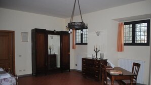 A room with a dining table, chairs, a chandelier, a fireplace, and a radiator.