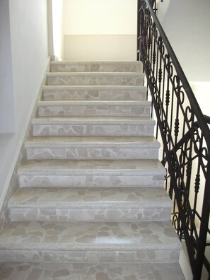A staircase with stone steps and a black wrought iron railing.