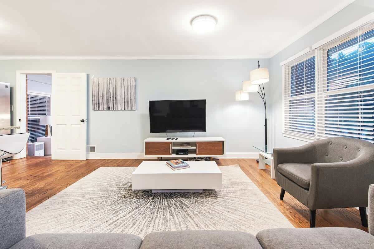Ein modernes Wohnzimmer mit einem Flachbildfernseher, einem weißen Couchtisch und einem grauen Sofa.