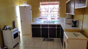 Une cuisine de taille réduite équipée d’un évier, d’une cuisinière et d’un lave-linge.