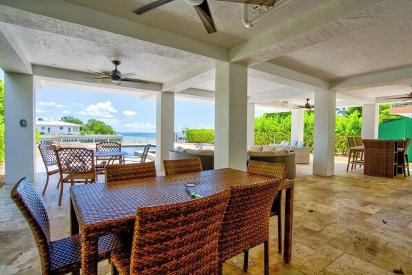 An outdoor patio with wicker furniture, a ceiling fan, and a view of the sea.