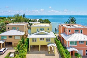 Un quartier résidentiel situé sur la côte, composé de trois maisons, chacune ayant un toit plat et un petit porche.