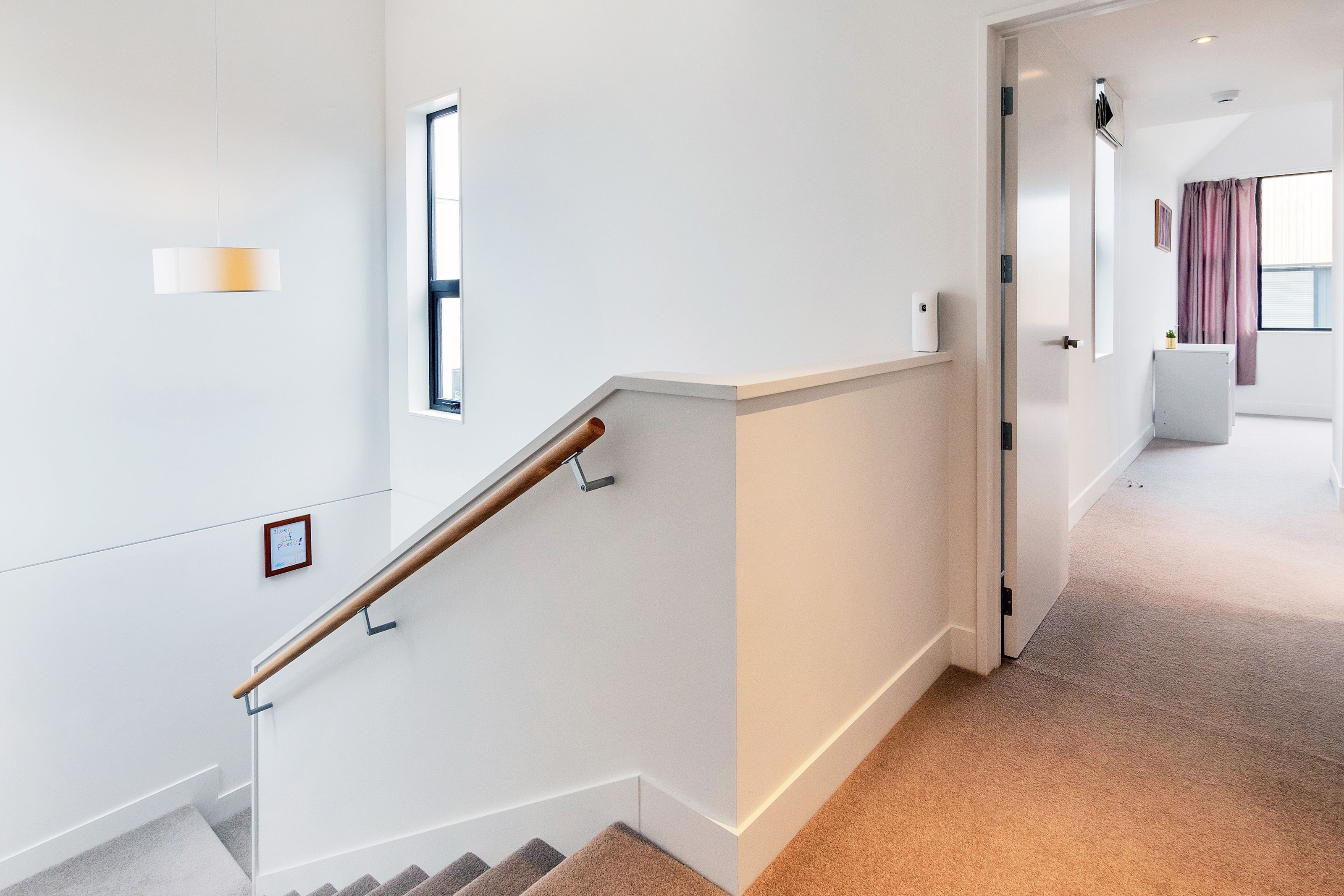 Un intérieur moderne avec un escalier, une porte donnant sur une autre pièce et une fenêtre avec des rideaux.