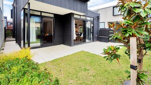 Une maison moderne à deux étages, dotée de grandes portes vitrées donnant sur un patio couvert.