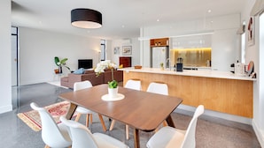 Une cuisine moderne avec des armoires blanches, un plan de travail en bois et un luminaire suspendu noir.