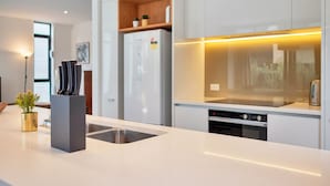 Une cuisine moderne avec des meubles blancs, un four encastré et un évier en acier inoxydable.