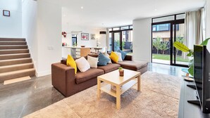 Un salon moderne avec un canapé marron, une table basse en bois et un téléviseur posé sur un meuble.