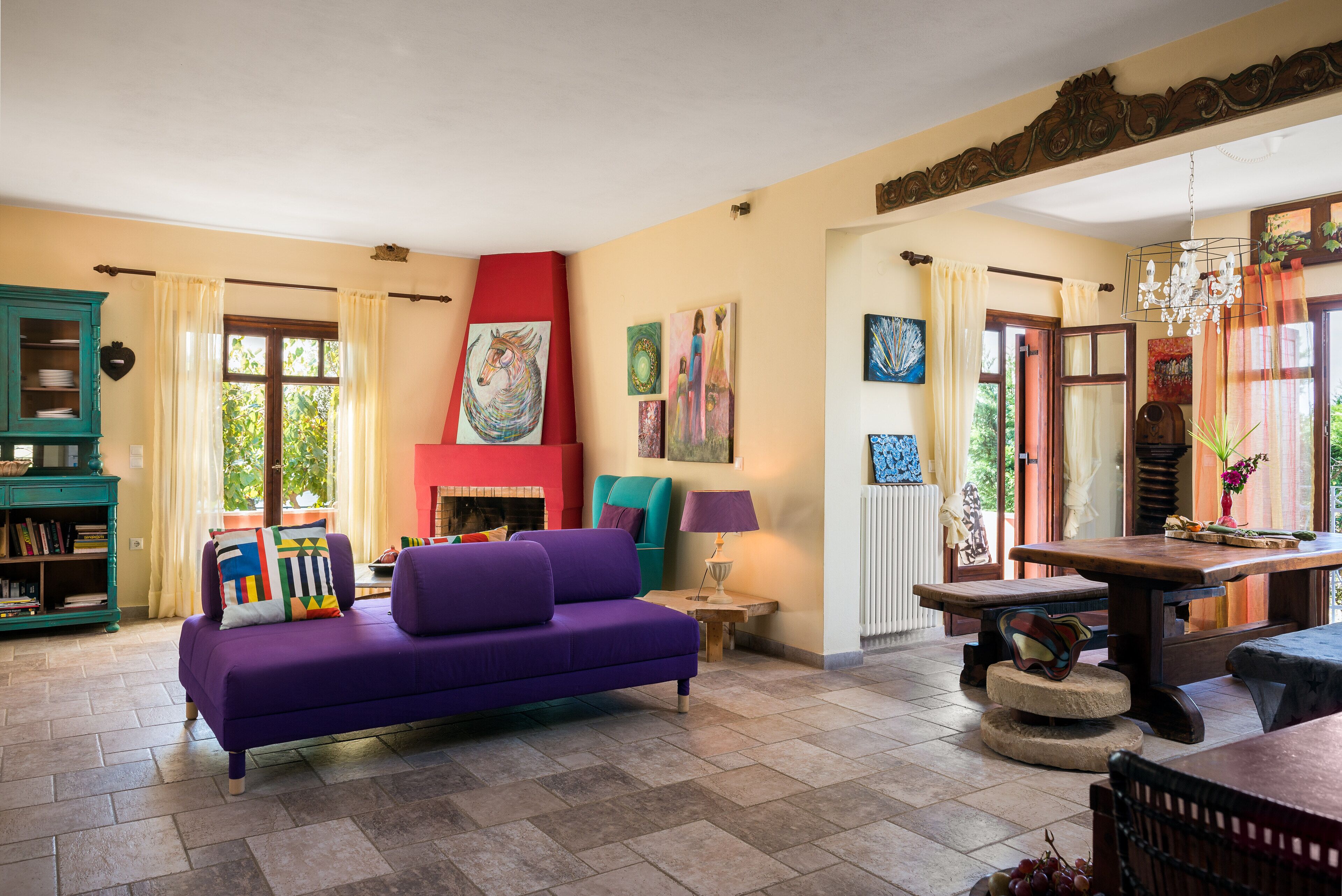 A cozy living room with a purple sofa, a fireplace, and artwork on the walls.