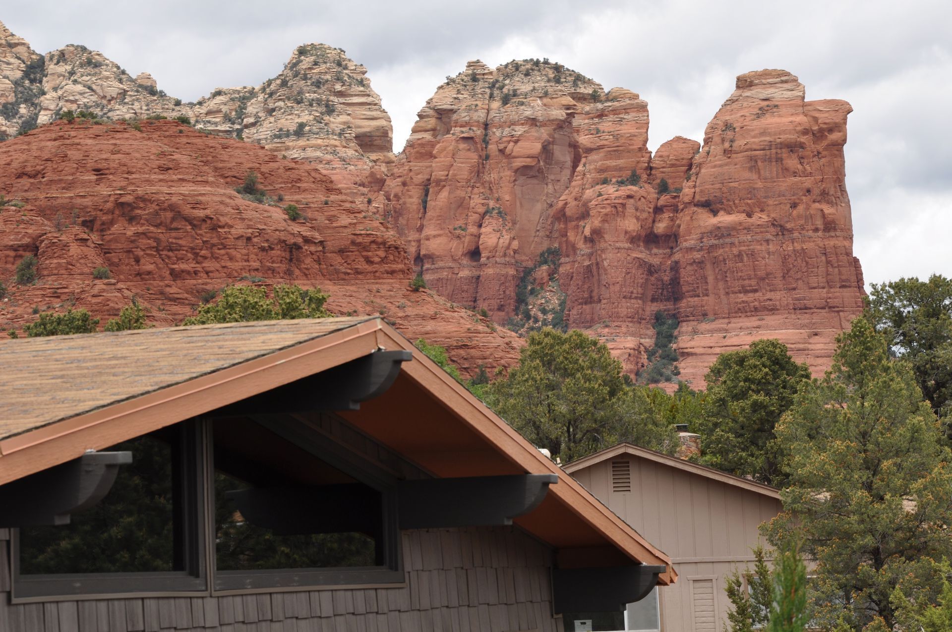 A building with a sloped roof and a window, set against a backdrop of red rock formations.
