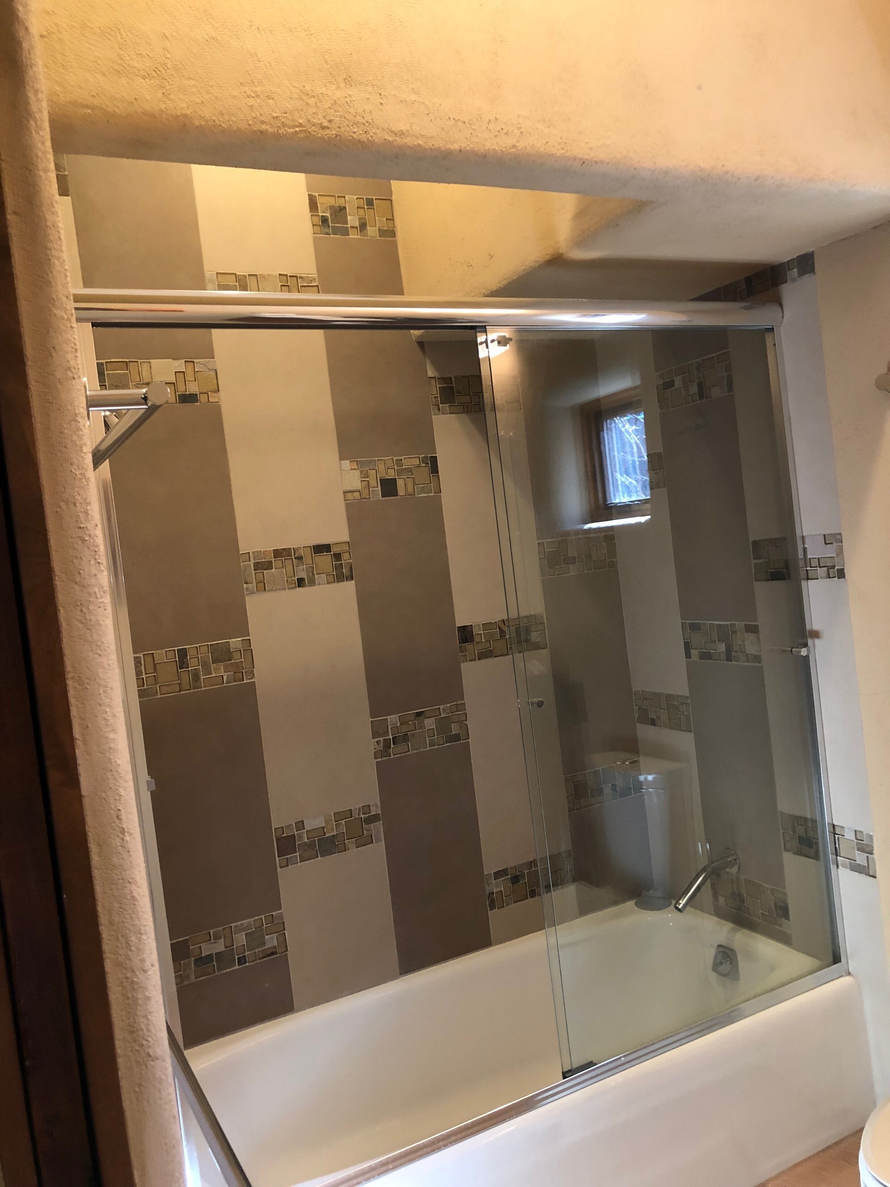 A shower area with a glass door and a bathtub.