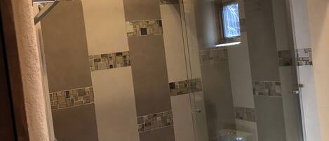 A shower area with a glass door and a bathtub.
