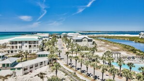 A coastal resort with beachfront villas, a swimming pool, and a pier extending into the ocean. - Sunset Jetty View! Enjoy one free beach chair set up and umbrella each day of yo (Destin)