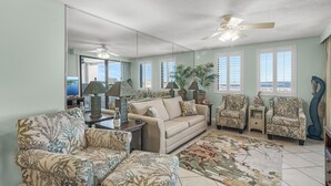 A living room with a beige sofa, patterned armchairs, a coffee table, and a large mirror. - Sunset Jetty View! Enjoy one free beach chair set up and umbrella each day of yo (Destin)