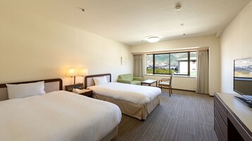 Habitación de hotel con dos camas, un escritorio, una silla, un televisor y una ventana con vistas al exterior.