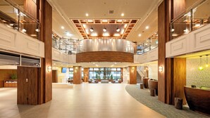 Un vestíbulo amplio con techo alto, detalles de madera y un área de estar central.