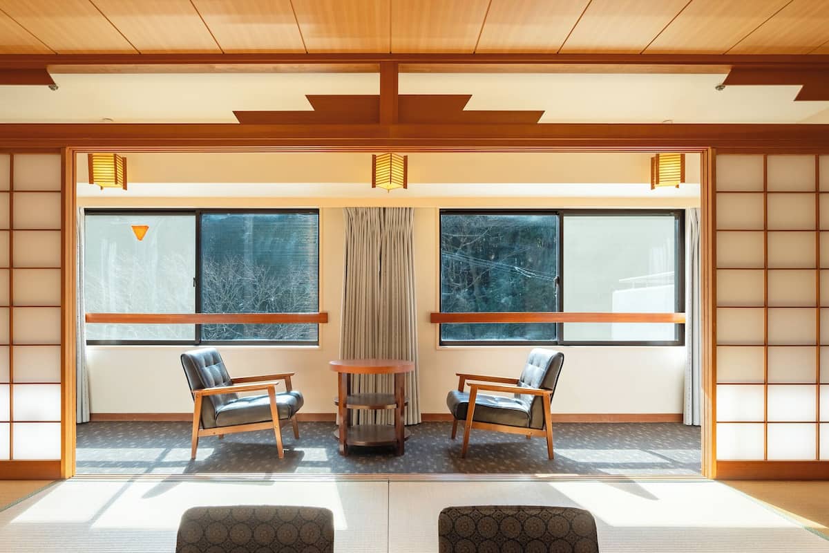 Una habitación japonesa tradicional con suelo de tatami, puertas correderas shoji y una mesa central con sillas.