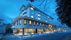 Un hotel moderno con fachada curva, ventanas amplias y una entrada bien iluminada.