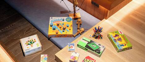 Una mesa de madera con diversos juguetes y juegos infantiles, incluyendo una estructura de madera, un trompo y varios juegos en cajas.