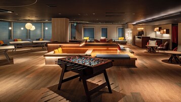 Un área de descanso moderna con mesa de futbolín, asientos y una cocina.
